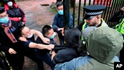 In this handout provided by Matthew Leung, Hong Kong protester Bob Chan scuffles with people who are trying to drag him into the Chinese consulate in Manchester, England, Oct. 16, 2022.
