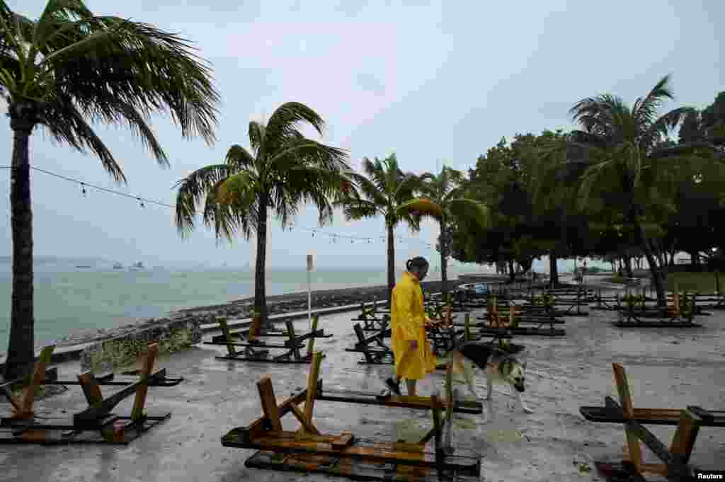 Un hombre camina con su perro a lo largo del paseo marítimo después de revisar su velero en el campo de amarre cuando el huracán Ian se acercaba a la costa del Golfo de Florida, EEUU, el 28 de septiembre de 2022.