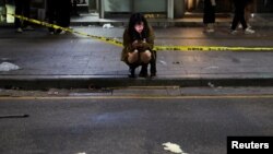 A woman uses a phone near the scene where many people died and were injured in a stampede during a Halloween festival in Seoul, South Korea, Oct. 30, 2022. 