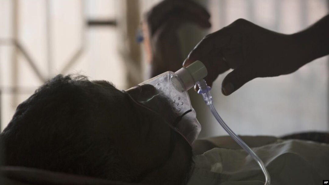 ARCHIVO - Un pariente ajusta la máscara de oxígeno de un paciente con tuberculosis en un hospital de TB en el Día Mundial de la Tuberculosis en Hyderabad, India, el 24 de marzo de 2018.