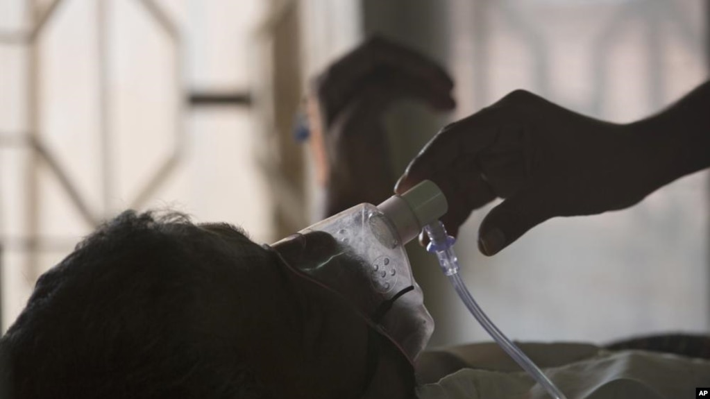 ARCHIVO - Un familiar ajusta la máscara de oxígeno de un paciente con tuberculosis, en un hospital en Hyderabad, India, el 24 de marzo de 2018.