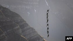 Soldiers of the Swiss Special Forces command perform suspended from an helicopter, during the annual live fire event over the Axalp in the Bernese Oberland, Switzerland.