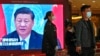 A security personnel checks a journalist near a TV screen showing image of President Xi Jinping at a media hotel in Beijing, Oct. 21, 2022.