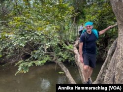 François Kieffer, operations manager for Belgian development agency Enabel in Guinea, uses a downed tree to cross a river.