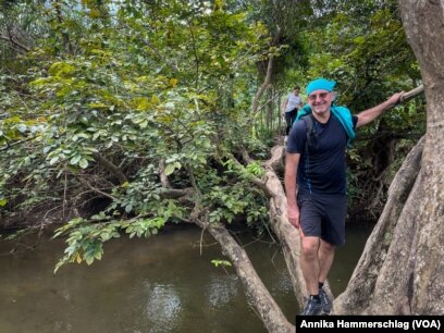 François Kieffer, operations manager for Belgian development agency Enabel in Guinea, uses a downed tree to cross a river.