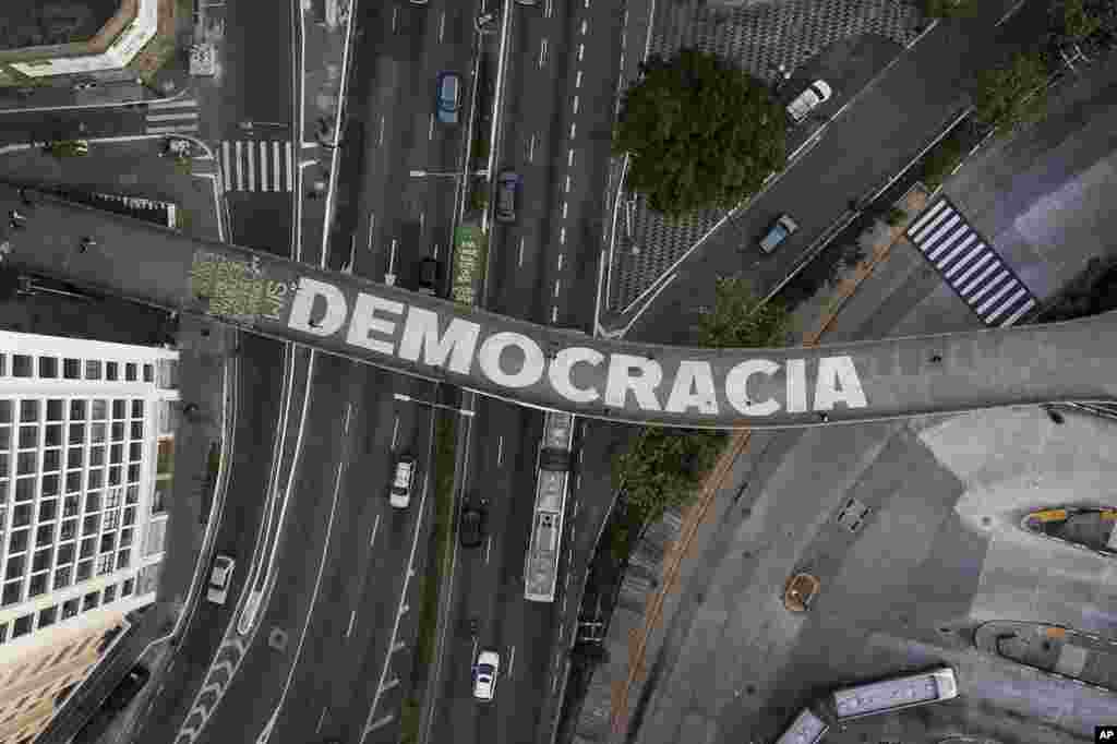 People walk on a pedestrian bridge that has written &quot;Democracy&quot; in Portuguese in Sao Paulo, Brazil, Oct. 26, 2022.