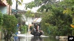 A resident wades through floodwaters, Thursday, Sept. 29, 2022, in Ubon Ratchathani province, northeastern Thailand.