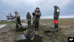 Russian recruits prepare their weapons as an instructor looks on, during military training at a firing range in Russia's Volgograd region, Oct. 27, 2022. 