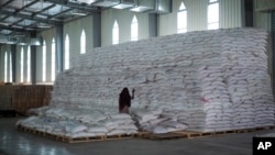 FILE - An aid worker walks next to a pile of sacks of food earmarked for the Tigray and Afar regions in a warehouse in Semera, in Ethiopia's Afar region, Feb. 21, 2022. One aid worker was reportedly killed and another wounded in an attack Friday in Ethiopia's Tigray region.