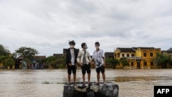 Boys stand on a rock on a flooded street after Typhoon Noru made landfall in Hoi An, Vietnam's Quang Nam Province on Sept. 28, 2022. 