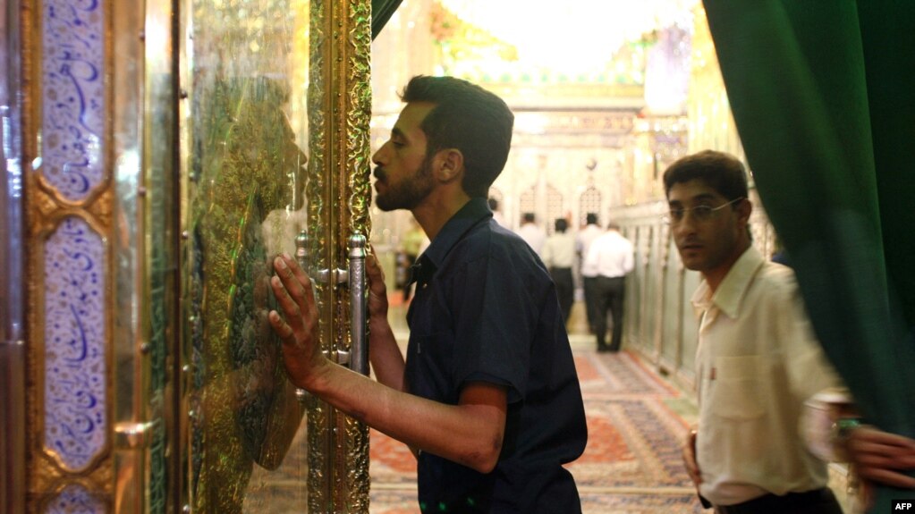 资料照片：一名伊朗男子正在亲吻灯王之墓的大门。(photo:VOA)