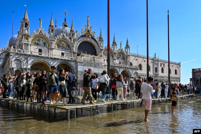 FILE - Tourists walk across elevated walkways outside St. Mark's Basilica on St. Mark's square in Venice, Italy, Sept. 27, 2022. (Photo by ANDREA PATTARO / AFP)