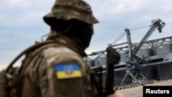 FILE - A Ukrainian serviceman stands in front of silos of grain at Odesa Black Sea port, in Odesa, Ukraine, July 29, 2022.