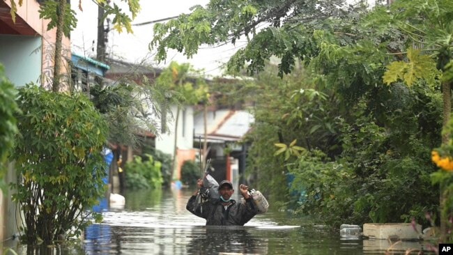 A resident wades through floodwaters, Thursday, Sept. 29, 2022, in Ubon Ratchathani province, northeastern Thailand.
