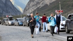 People walk toward the border crossing at Verkhny Lars between Georgia and Russia Wednesday, Sept. 28, 2022. (AP Photo)