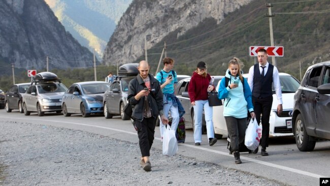 People walk toward the border crossing at Verkhny Lars between Georgia and Russia Wednesday, Sept. 28, 2022. (AP Photo)