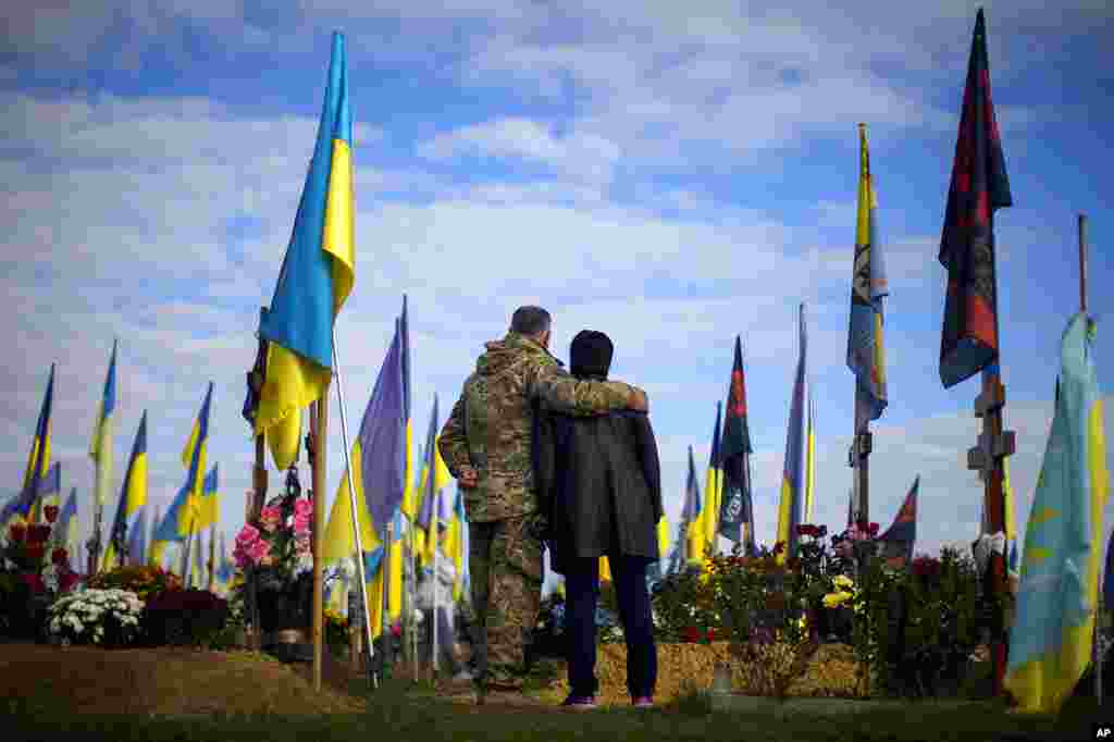 Parents of recently killed Ukrainian serviceman Ruslan Zhumaboev stand next to his grave in a cemetery during Ukraine Defenders Day in Kharkiv, Ukraine.