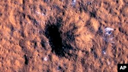 In this image made available by NASA on Thursday, Oct. 27, 2022, boulder-size blocks of water ice are seen around the rim of an impact crater on Mars. The crater was formed Dec. 24, 2021, by a meteoroid strike. (NASA/JPL-Caltech/University of Arizona via AP)