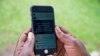 FILE - A woman reads a message on social media on her phone in Kampala, Uganda, July 5, 2018. Activists say the vague wording in a social media usage law signed Oct. 13, 2022, will be used to silence government critics. 