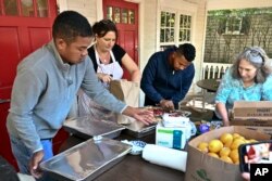 FILE - Volunteers prepare food for immigrants outside St. Andrews Episcopal Church, Sept. 15, 2022, in Edgartown, Mass., on Martha's Vineyard.