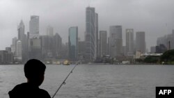 A man fishes in the harbor while it rains in Sydney, Oct. 6, 2022.