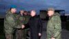 Russian President Vladimir Putin, center, greets Russian officers as he and Russian Defense Minister Sergei Shoigu, right, visit a military training center for mobilized reservists in Ryazan Region, Russia, Oct. 20, 2022.