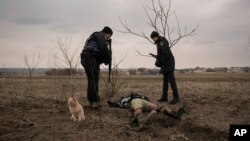 Police officers identify the body of a Ukrainian man killed while his village was occupied by Russian troops, in the village of Andriivka, Ukraine, April 5, 2022.
