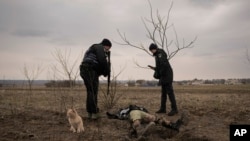 Офицеры украинской полиции идентифицируют останки украинского военнослужащего, убитого, когда это село было оккупировано российской армией. Украина. 5 апреля 2022 г.