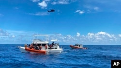 This image provided by the U.S. Coast Guard shows Coast Guard law enforcement crews aiding people from an unsafe and overloaded 40-foot cabin cruiser about 20 miles off Boca Raton, Fla., Oct. 12, 2022. 