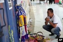 Seorang pria berdoa untuk para korban injak-injak pertandingan sepak bola di depan gerbang 13 Stadion Kanjuruhan Malang, 4 Oktober 2022. (Foto: AP)