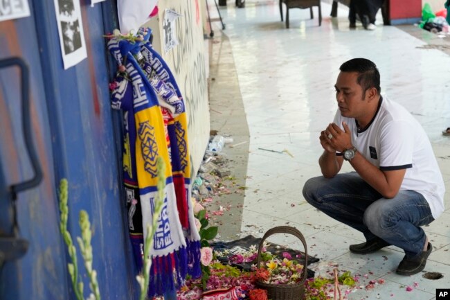 Seorang pria berdoa untuk para korban injak-injak pertandingan sepak bola di depan gerbang 13 Stadion Kanjuruhan Malang, 4 Oktober 2022. (Foto: AP)