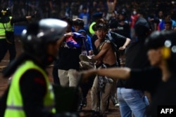 Sekelompok orang menggendong seorang pria usai pertandingan sepak bola antara Arema FC dan Persebaya Surabaya di Stadion Kanjuruhan, Malang, Jawa Timur. (Foto: AFP)