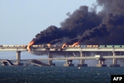 Black smoke billows from a fire on the Kerch bridge that links Crimea to Russia, after a truck exploded, near Kerch, Oct. 8, 2022.
