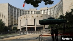 FILE - Paramilitary police officers stand guard in front of the headquarters of the People's Bank of China, the central bank (PBOC), in Beijing, Sept. 30, 2022. 