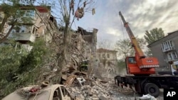 In this photo provided by the Ukrainian Emergency Service, rescuers work at the scene of a building damaged by shelling in Zaporizhzhia, Ukraine, Oct. 6, 2022.