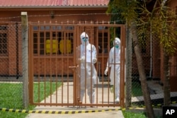 Doctors wearing protective equipment are seen after visiting a patient who was in contact with an Ebola victim, in the isolation section of Entebbe Regional Referral Hospital in Entebbe, Uganda Thursday, Oct. 20, 2022. (AP Photo/Hajarah Nalwadda)