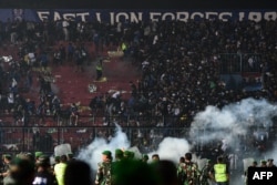 This picture taken on October 1, 2022 shows security personnel (lower) on the pitch after a football match between Arema FC and Persebaya Surabaya at Kanjuruhan stadium in Malang, East Java.