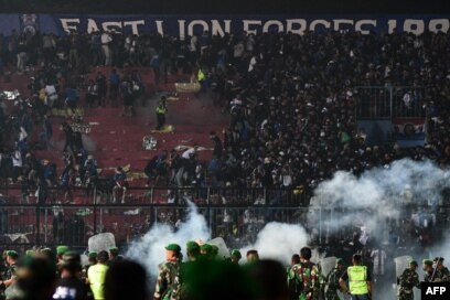 Petugas keamanan (bawah) di lapangan usai pertandingan sepak bola antara Arema FC dan Persebaya Surabaya di Stadion Kanjuruhan, Malang, Jawa Timur. (Foto: AFP)