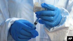 FILE - A health care worker from the World Health Organization prepares to administer an Ebola vaccine to a patient in Mangina, Democratic Republic of Congo, Aug. 8, 2018.