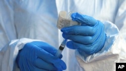 FILE - A healthcare worker from the World Health Organization prepares to administer an Ebola vaccine to a patient in Mangina, Democratic Republic of Congo, Aug. 8, 2018.