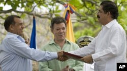 Honduras' President Porfirio Lobo, left, and Honduras' ousted President Manuel Zelaya, right, shake hands after signing an agreement as Colombia's President Juan Manuel Santos applauds in Cartagena, Colombia, May 22, 2011.