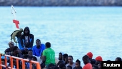 Beberapa migran menunggu untuk diturunkan dari perahu kayu di pelabuhan Arguineguin, di pulau Gran Canaria, Spanyol, 20 Oktober 2024. (Borja Suarez/REUTERS)