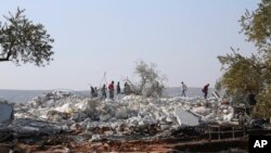 FILE - People look at a destroyed houses near the village of Barisha, in Idlib province, Syria, Oct. 27, 2019, after an operation by the U.S. military which targeted Abu Bakr al-Baghdadi, the shadowy leader of the Islamic State group.