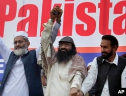 FILE - Leader of Hizbul Mujahideen, Syed Salahuddin, center, joins hands with leaders of Jamaat-e-Islami, Sirajul Haq, left, and Mian Aslam, during an anti-India rally in Islamabad, Pakistan, July 24, 2016.