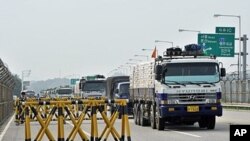 South Korean trucks carrying 300 tons of flour drive past a military checkpoint before crossing the inter-Korean border in Paju, north of Seoul, on July 26, 2011