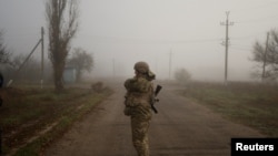 A Ukrainian serviceman stands on a street in a village near the newly recaptured city of Snihurivka, in Mykolaiv region, Ukraine Nov. 10, 2022.