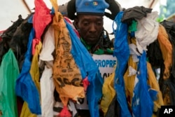 The environmental activist Modou Fall, who many simply call "Plastic Man," wears his uniform before an event about environmental health and pollution management in Dakar, Senegal, Nov. 8, 2022.