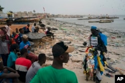 FILE - The environmental activist Modou Fall, who many simply call "Plastic Man," talks to the locals about the pollution caused by plastic bags at the Yarakh Beach littered by trash in Dakar, Senegal, Nov. 8, 2022.