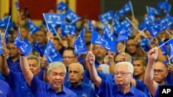 Organisasi Nasional Melayu Bersatu (UMNO) dan koalisi Barisan Nasional (Front Nasional) Presiden Ahmad Zahid Hamidi, kiri depan, dan Perdana Menteri sementara Ismail Sabri Yaakob, kanan depan, mengibarkan bendera di Kuala Lumpur, Malaysia pada 1 November 2022. (Foto : AP)