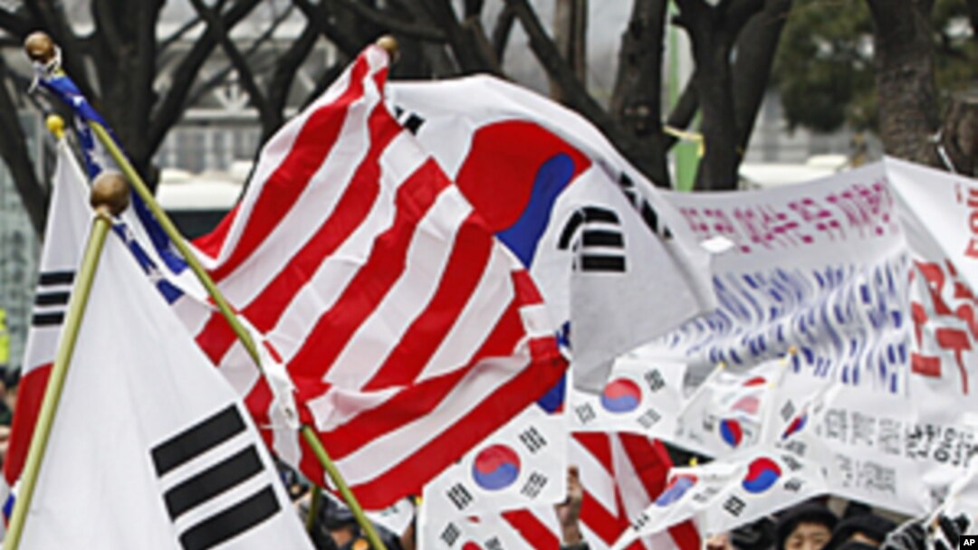 South Korean activists cheer as they wave flags of the United States and South Korea to celebrate the free trade agreement, or FTA, with the United States during a rally near the U.S. Embassy in Seoul, South Korea, March 14, 2012. 